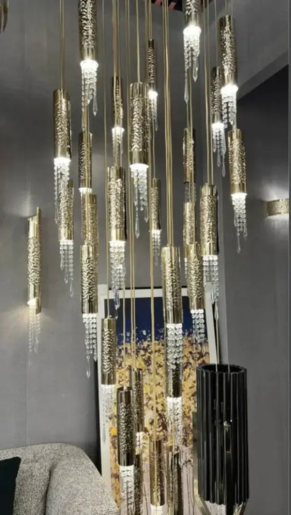 A modern decorbites crystal led large chandelier with gold-toned etched cylinders and crystal droplets for staircase lighting