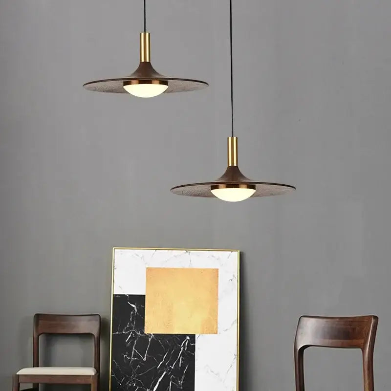 Two modern pendant lights with brass stems and dark textured shades in decorbites flying saucer solid wood style