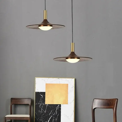Two modern pendant lights with brass stems and dark textured shades in decorbites flying saucer solid wood style