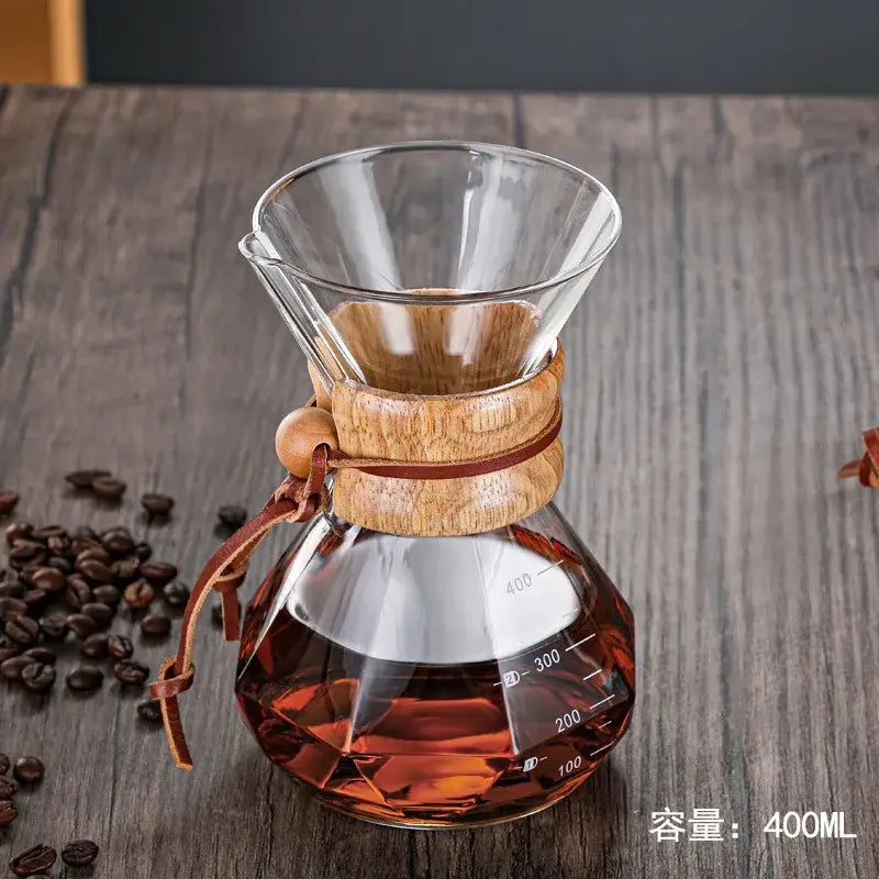 Modern decorbites glass coffee maker with wooden collar and leather tie filled with amber brewed coffee for kitchen drip
