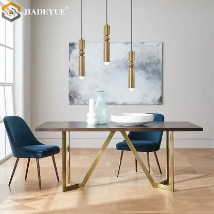 Modern dining table with dark wood top and gold-toned geometric metal legs paired with decorbites golden led chandelier