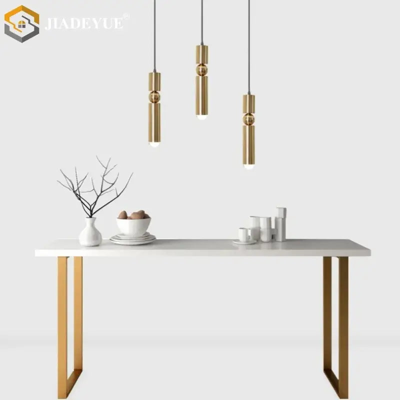 Three modern brass cylindrical pendant lights with spherical accents in a decorbites golden led chandelier for dining room