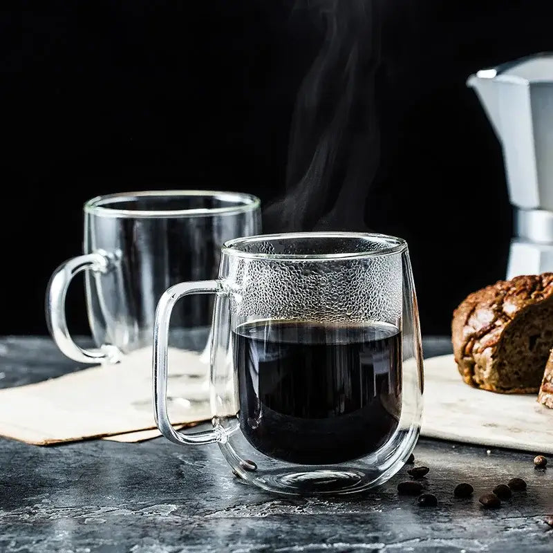 Modern double walled glass coffee mug by decorbites with textured surface and clear handle filled with steaming dark liquid
