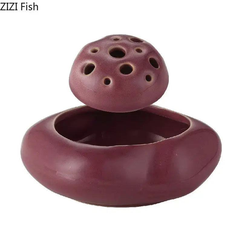 A maroon lotus seedpod ceramic incense burner with lotus-shaped perforated lid and smooth rounded base for living room decor