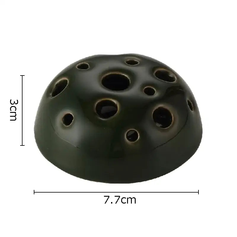 Dark green lotus seedpod ceramic ocarina with circular holes used as a modern earthy incense burner decor