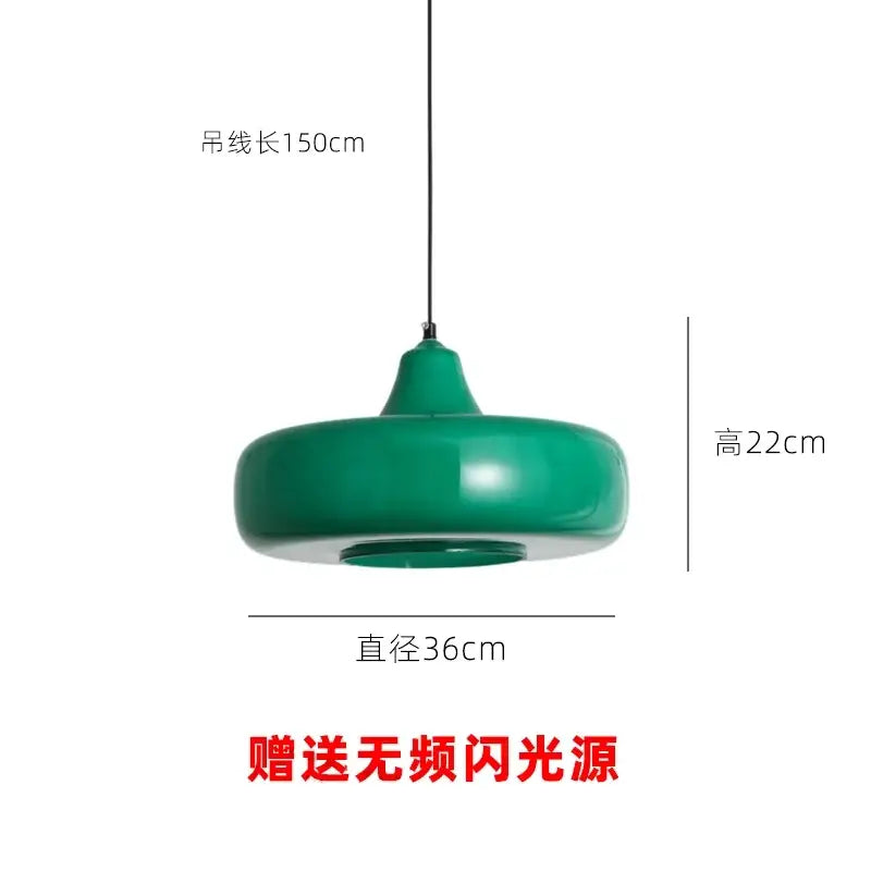 Modern emerald green glass pendant light with a sleek rounded disc shape and smooth curved edges for dining rooms