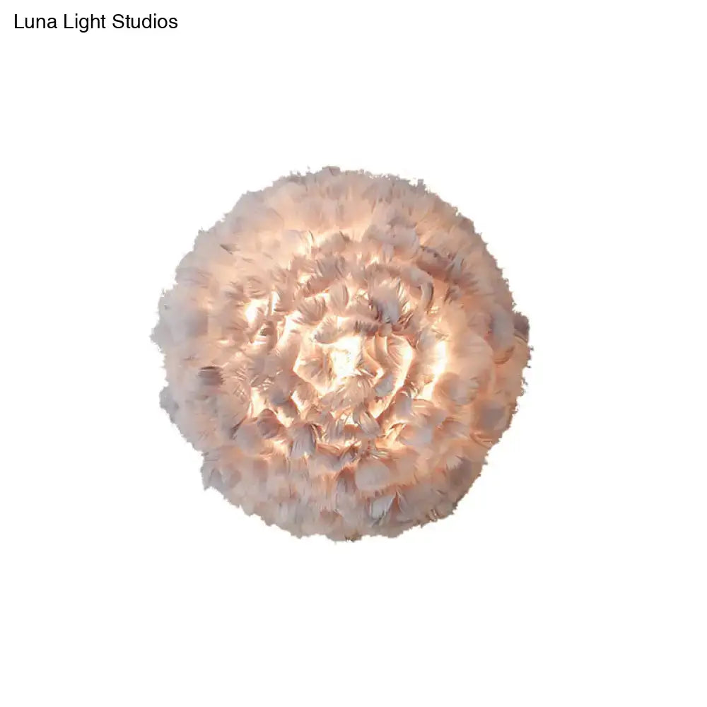 Modern feather material wall light with layered grey and white feathers emitting a warm glow for bedroom use