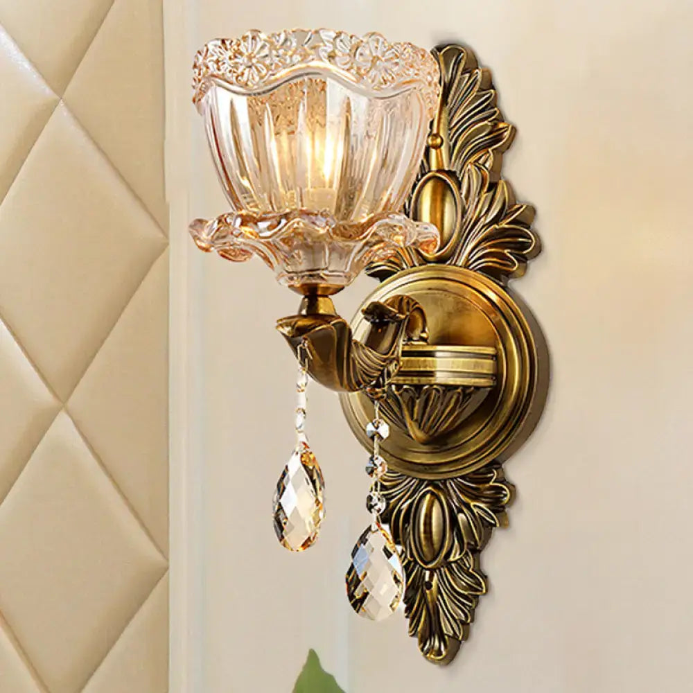 Modern floral brass wall sconce with gold tone, amber glass shade, and teardrop crystal drop for living room lighting