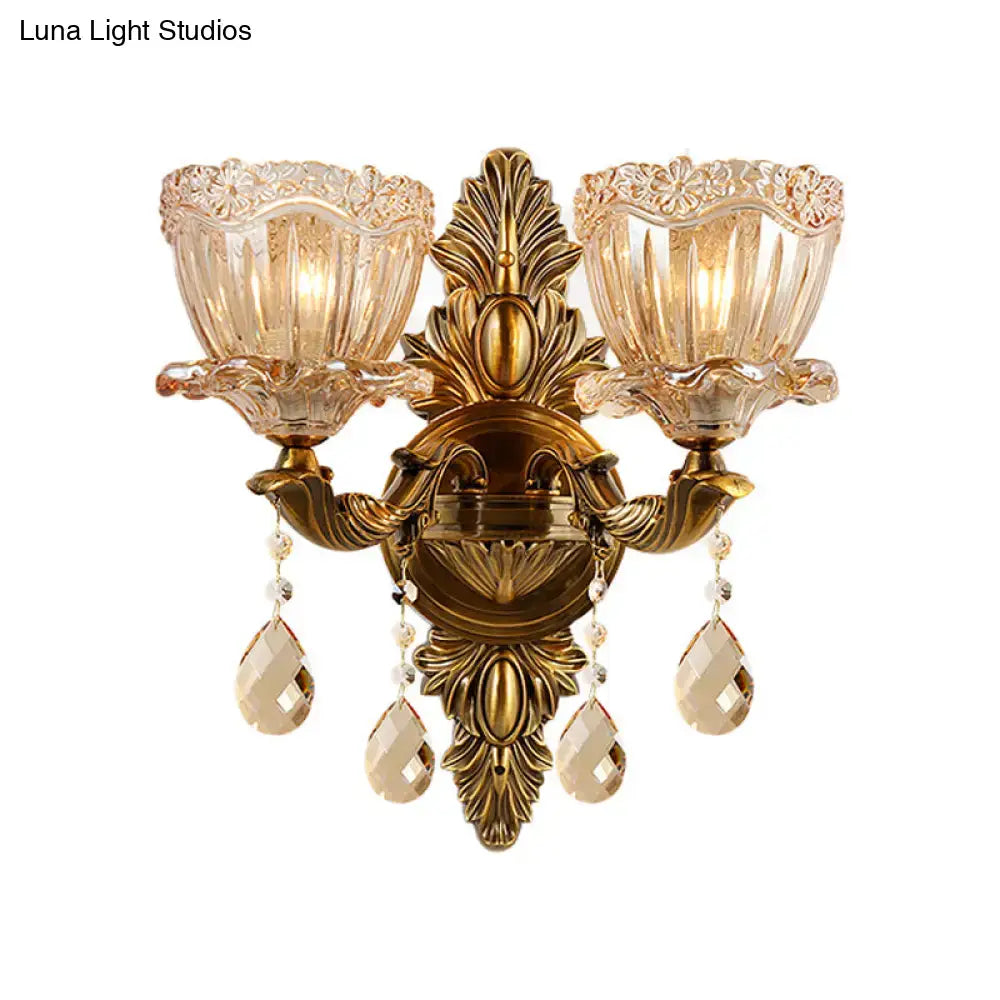 Antique brass two-light wall sconce with modern floral leaf motifs amber glass shades and teardrop crystal drop pendants