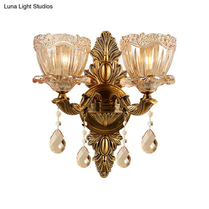 Antique brass two-light wall sconce with modern floral leaf motifs amber glass shades and teardrop crystal drop pendants