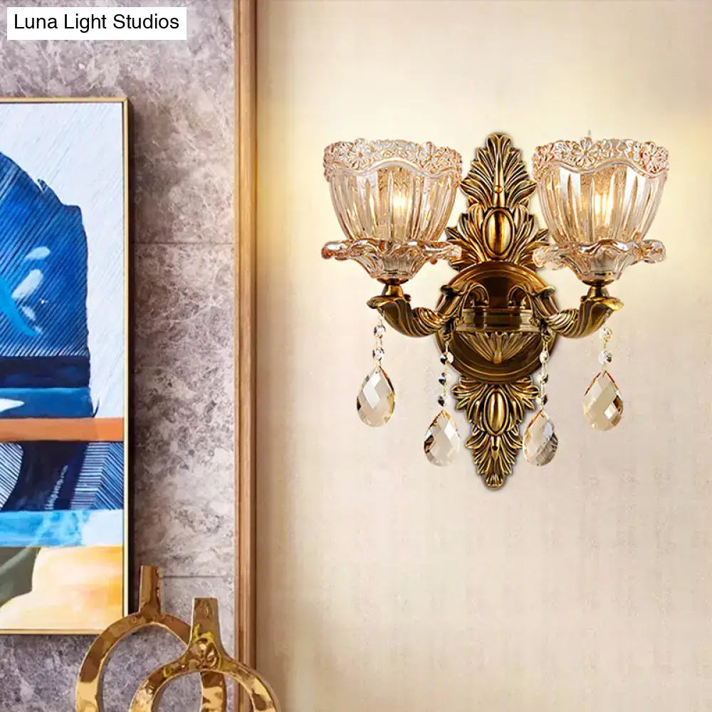 Antique brass two-light modern floral wall sconce with ornate leaf motifs and teardrop crystal drop for living room