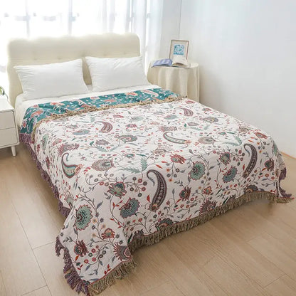 A cream and teal decorbites cooling cotton blanket with paisley patterns and fringe edges for bedroom decor