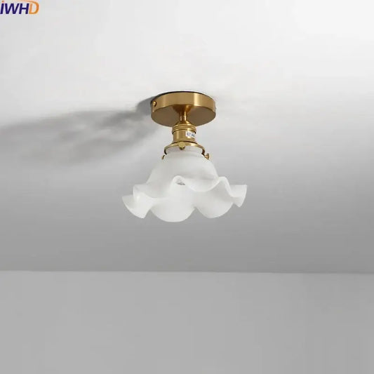 A delicate white frosted glass led ceiling light with ruffled flower design and polished brass mounting fixture