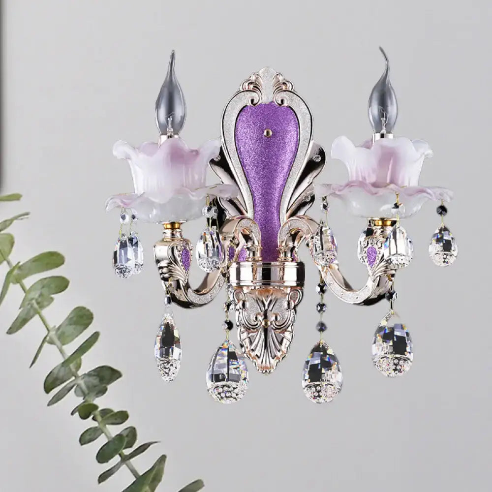 Elegant purple and silver crystal chandelier with floral accents complementing frosted glass purple wall sconce with teardrop crystal