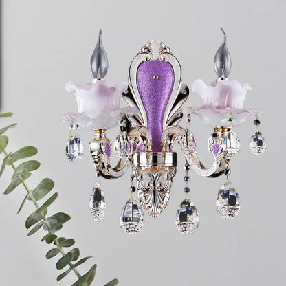 Elegant purple and silver crystal chandelier with floral accents complementing frosted glass purple wall sconce with teardrop crystal