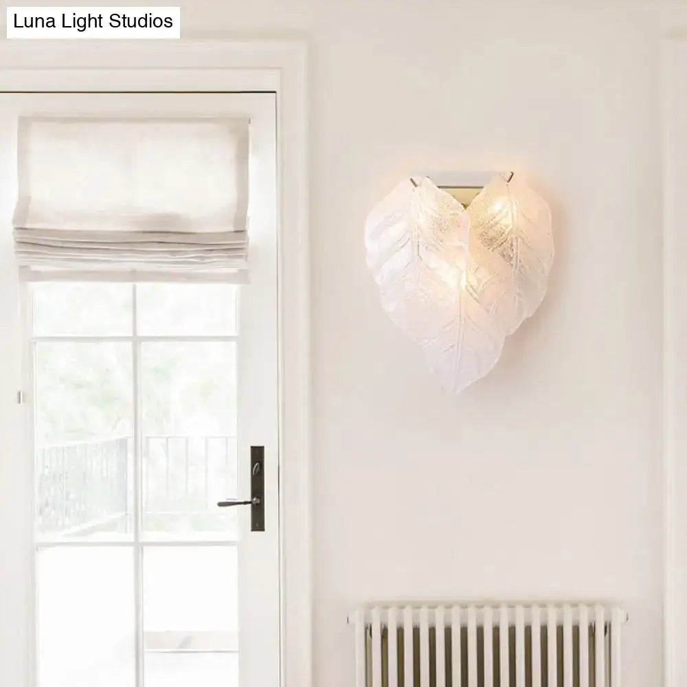 Modern frosted white glass leaf wall sconce light with translucent veined design and warm glowing sconce light