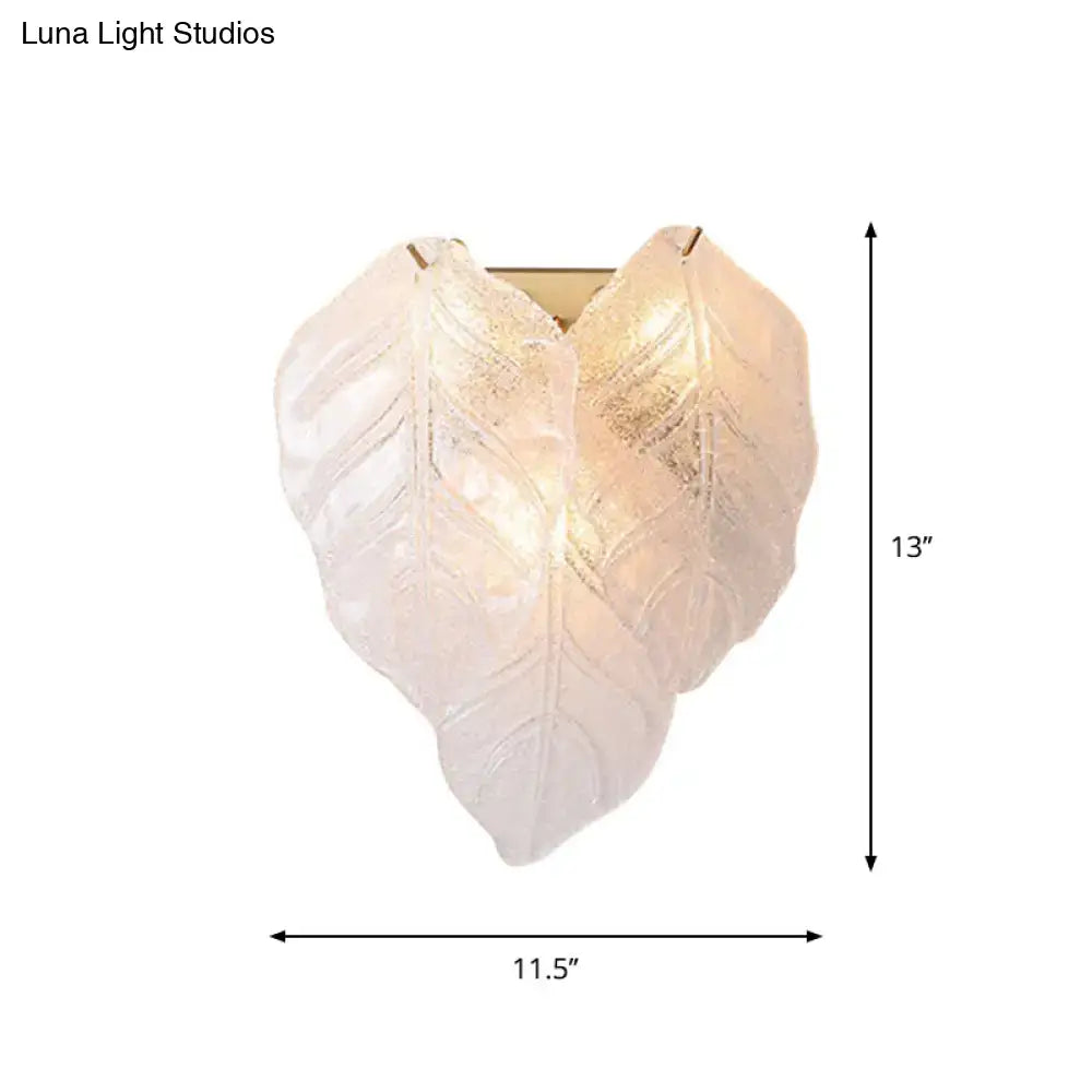Modern frosted white glass leaf wall sconce light with translucent overlapping leaves and warm gold leaf detailing