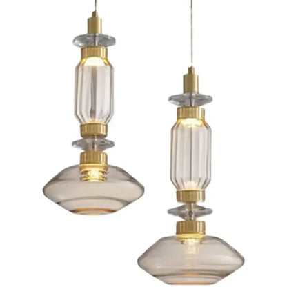 Two elegant pendant lights with clear faceted glass shades and gold accents featured in a decorbites glass chandelier