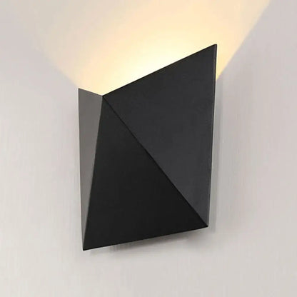 Modern geometric black metal wall sconce with angular facets and warm focused light beam wall lamp for bedroom