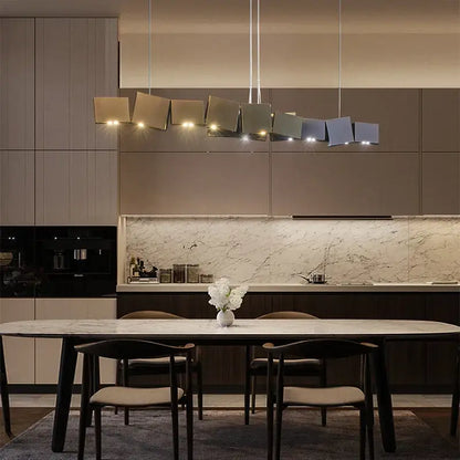 Modern geometric bronze and dark gray box shape pendant light with matte metallic finish above dining table decorbites