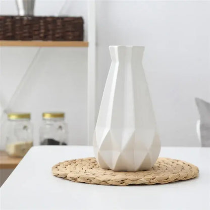 A sleek white decorbites ceramic diamond vase with a geometric faceted design on a woven placemat for living room decor