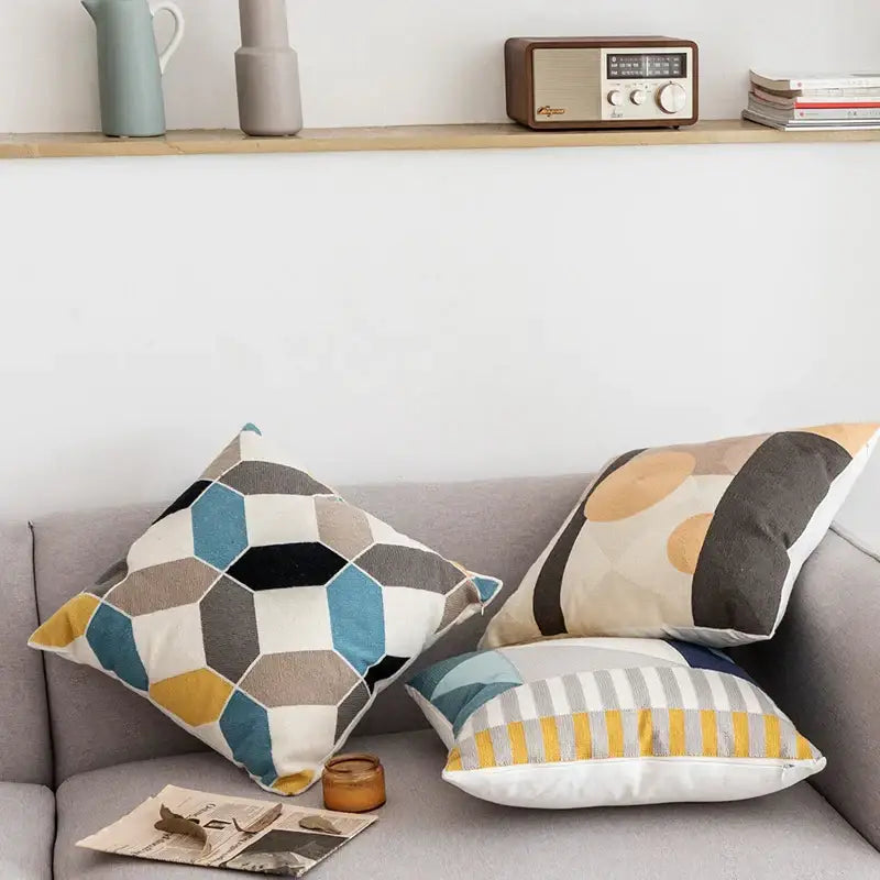 Three modern geometric embroidery cushion covers in muted blue gray beige yellow and black decorbites geometric embroidery design on sofa
