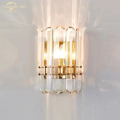 Elegant gold-toned modern geometric nordic wall sconce with faceted crystal columns refracting light beautifully