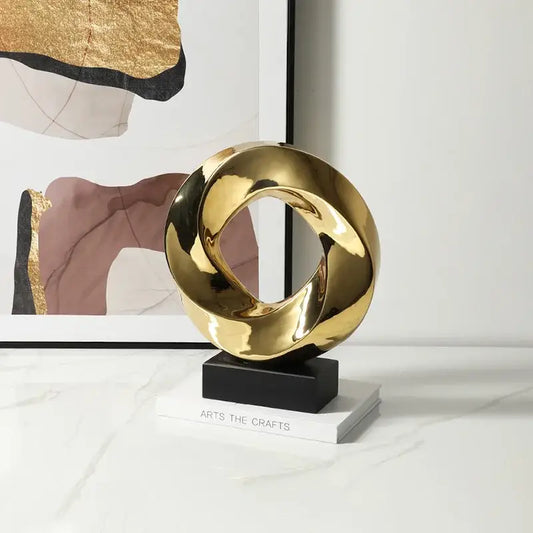 Shiny gold abstract geometric gold hollowed sculpture with intertwined loops on black base for home decor