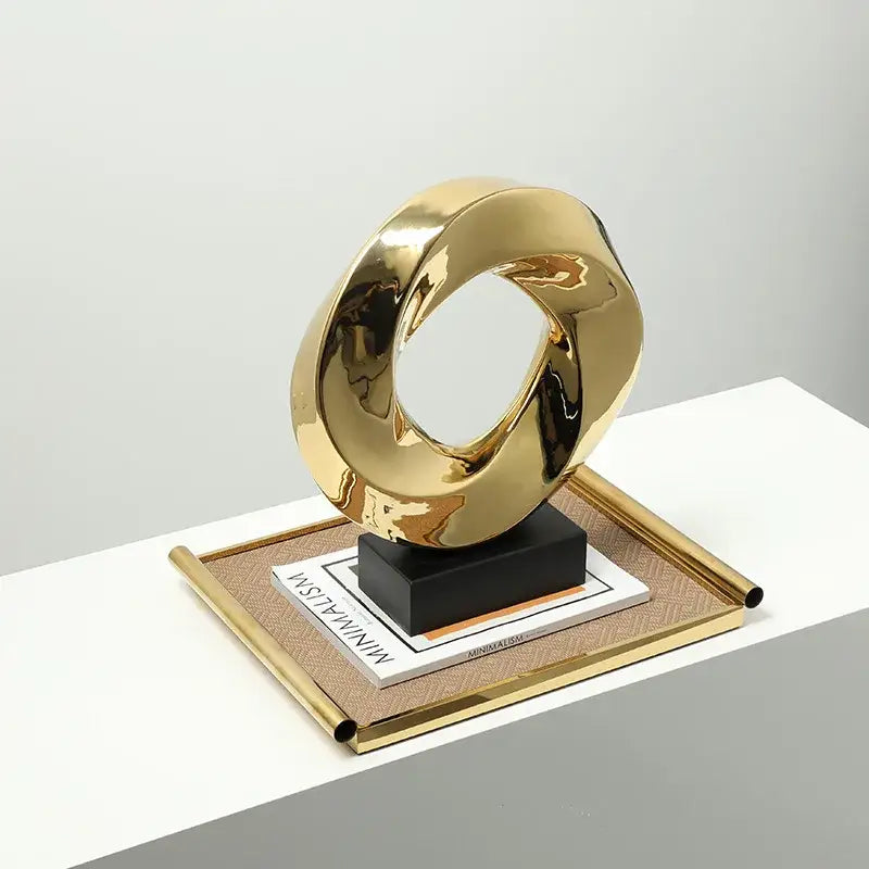 Modern geometric gold ring sculpture with a smooth reflective surface and intertwined gold ring hollow design for living room decor