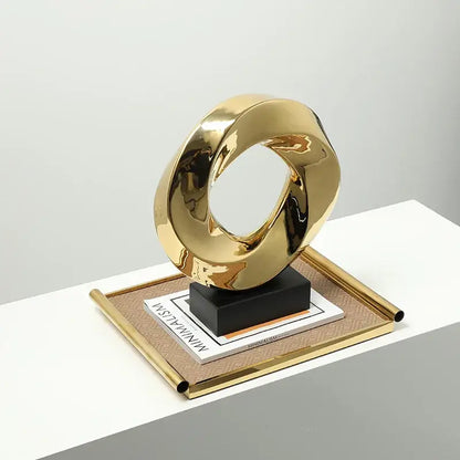 Modern geometric gold ring sculpture with a smooth reflective surface and intertwined gold ring hollow design for living room decor