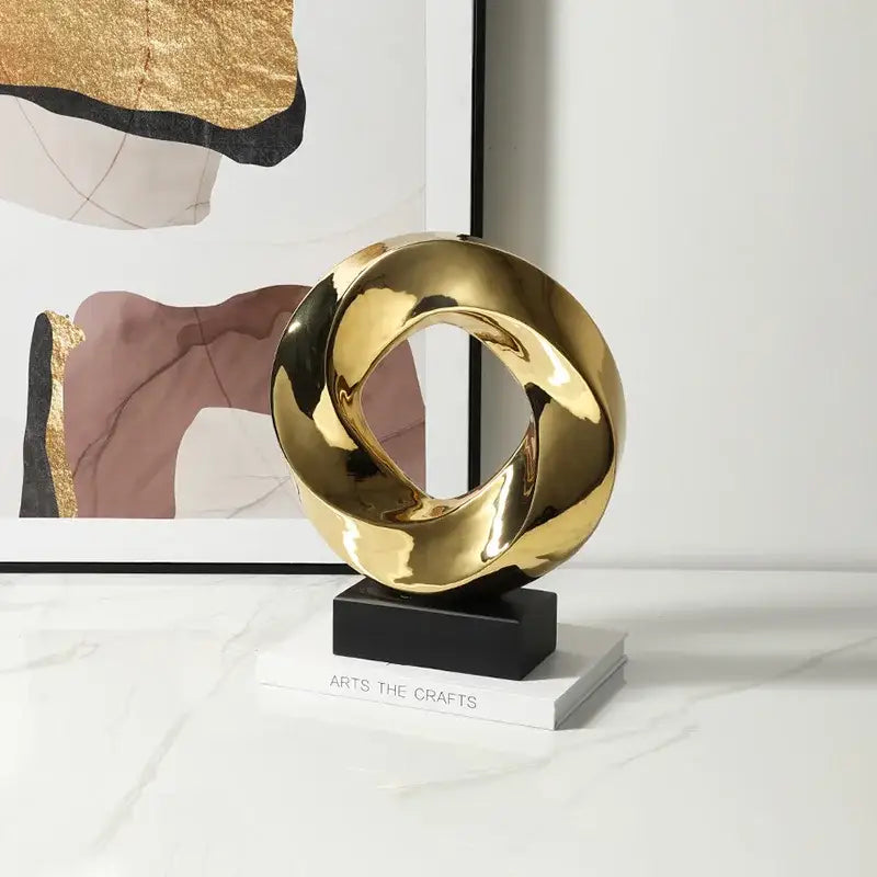 Shiny gold abstract geometric gold ring hollow sculpture with intertwined loops on black base for living room decor
