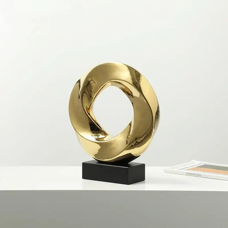 Shiny gold geometric gold ring hollow abstract sculpture with intertwined loops on black base for living room decor