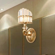 Modern geometric gold wall lamp with tiered clear crystal panels and polished brass base for living room sconce