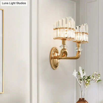 Gold-toned modern geometric wall lamp with two crystal chandelier arms and clear glass prisms for living room sconce