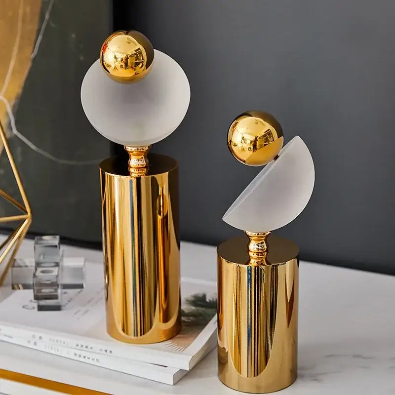 Two modern abstract geometric golden ball sculptures with polished gold bases and frosted glass orbs for living room decor