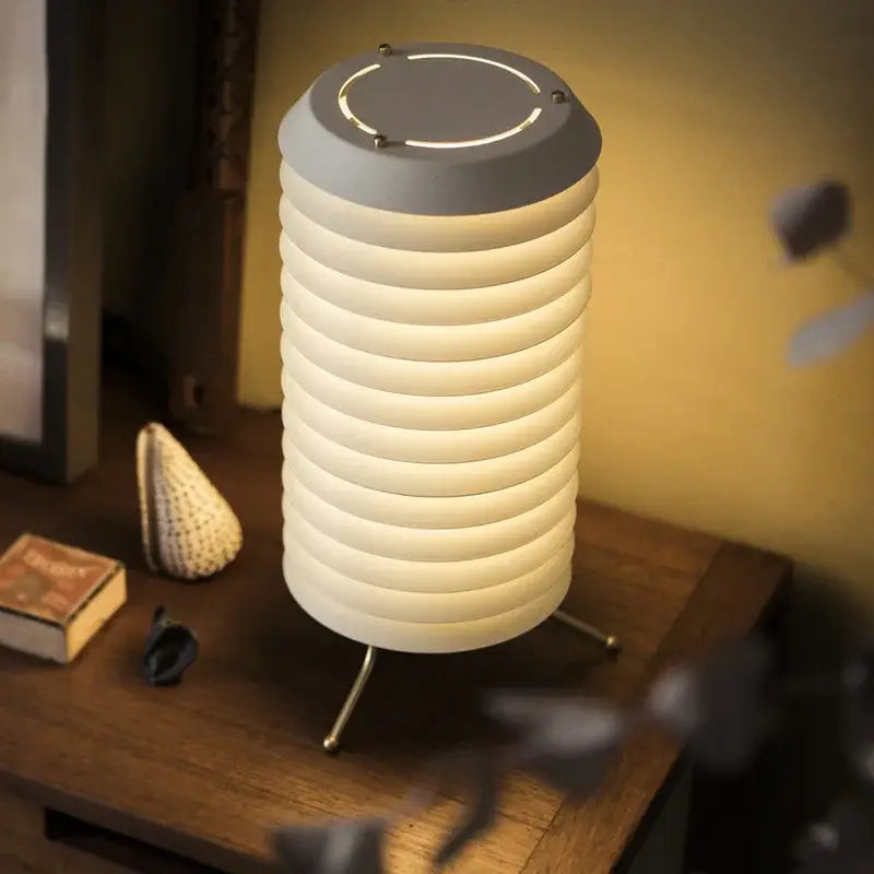 A modern decorbites geometric iron table lamp with a ribbed white body gray top and three slender metal legs for living room decor