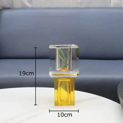 Clear acrylic vase with golden base holding small green plant as decorbites geometric square artificial flowers decor