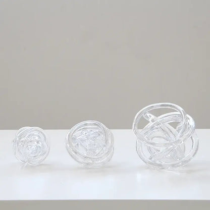 Three transparent glass coil wound balls of varying sizes with intricate interwoven circular designs for living room decor