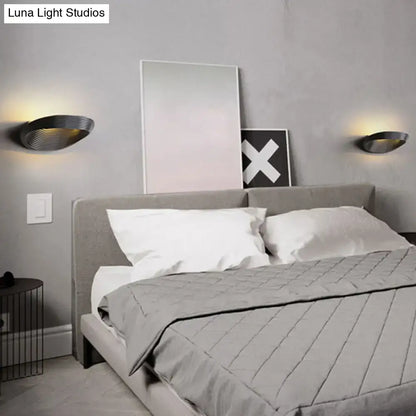 Modern geometric black metal wall light with sleek curved design providing warm white light for bedroom ambiance