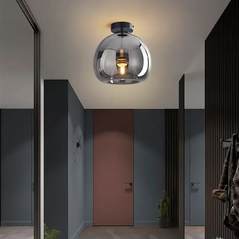 A sleek modern glass ball led ceiling light with brass and black metallic finish and exposed bulb for bedroom decorbites