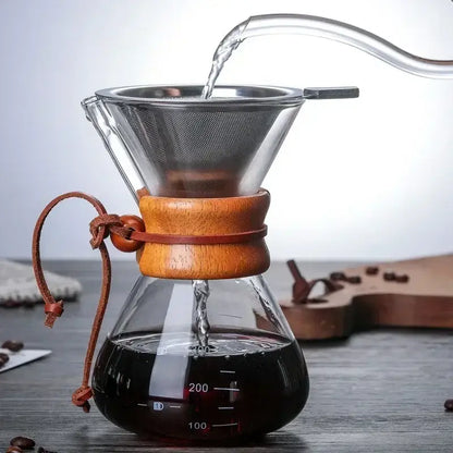 Clear glass chemex coffee kettle with wooden collar and steel filter drip brewer pouring hot water