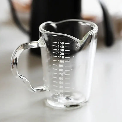 Modern glass cup with wooden handle and heart-shaped spout measuring jug for milk latte marked in milliliters