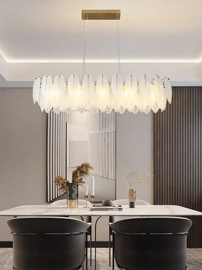 A modern elongated glass feather chandelier with translucent white shades and a gold-toned brass ceiling mount