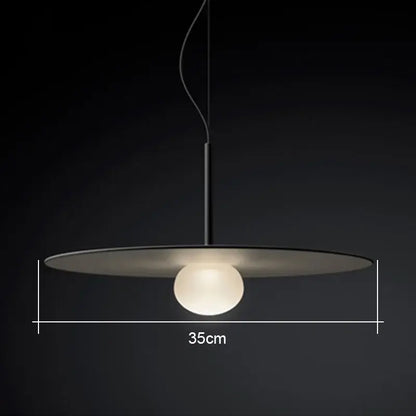Minimalist black pendant light with a sleek glass flying saucer shade and glowing frosted globe for living room use