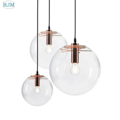 Set of three clear glass globe chrome pendant lights with copper-toned fixtures for modern dining room lighting
