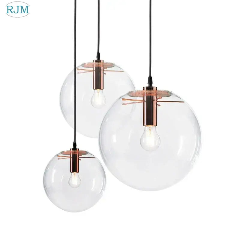 Set of three clear glass globe chrome pendant lights with copper fixtures and exposed bulbs for dining room use
