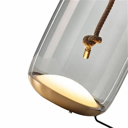 Modern glass knot table lamp with translucent gray glass shade brass base and hanging rope detail for bedroom decorbites brokis knot
