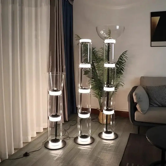 Three modern glass led floor lamps with stacked cylindrical sections and glowing white led rings for living room use