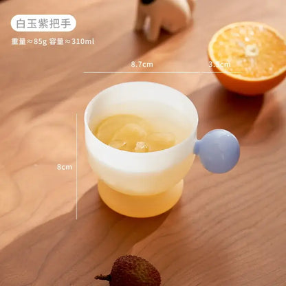 Modern glass spherical handle coffee mug with translucent white yellow silicone body and light blue spherical handle filled with iced tea