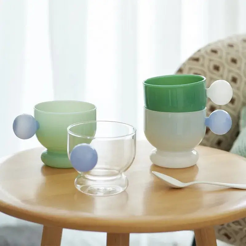 Pastel green and white gradient ceramic coffee mug with rounded blue glass spherical handle for kitchen use